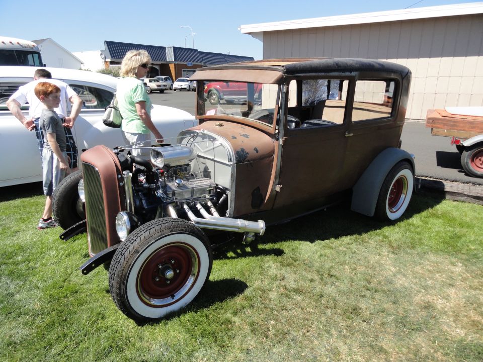 Brown hot rod sedan with exposed engine and whitewall tires