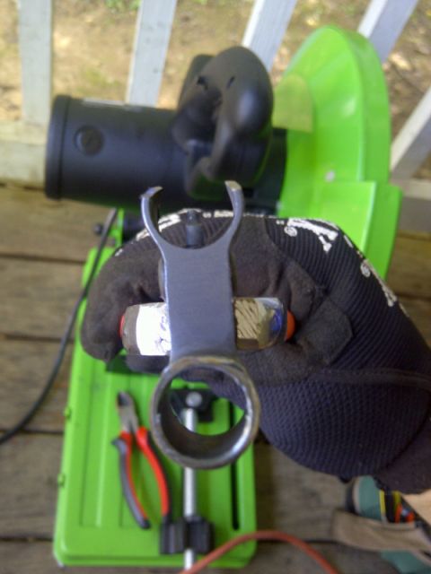 1989 Ford Bronco - A metal part is held in front of a green cutting tool, with pliers visible below.