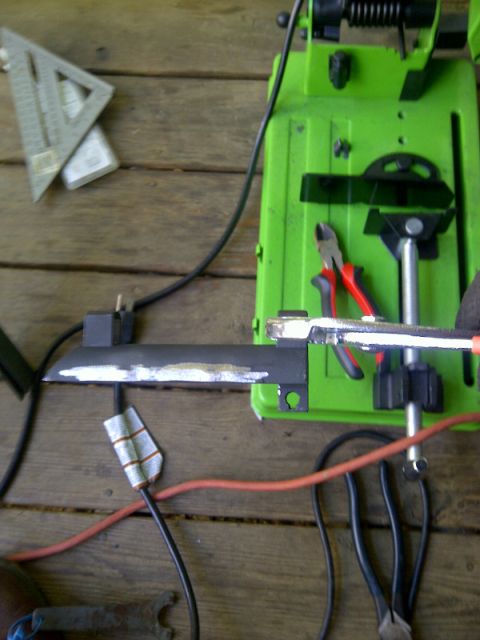 1989 Ford Bronco - Metal part being cut on a chop saw with tools and a speed square on a wooden surface.