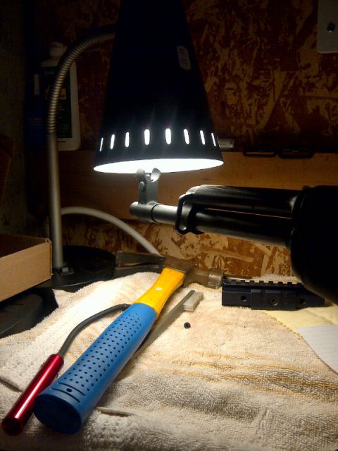 1989 Ford Bronco - Tools and gun components are laid out on a towel under a desk lamp for assembly or maintenance.