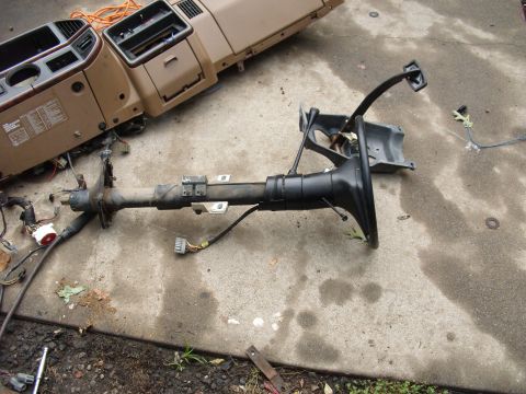 1988 Ford Bronco - Dashboard and steering column removed from a vehicle and placed on concrete for repair or replacement.