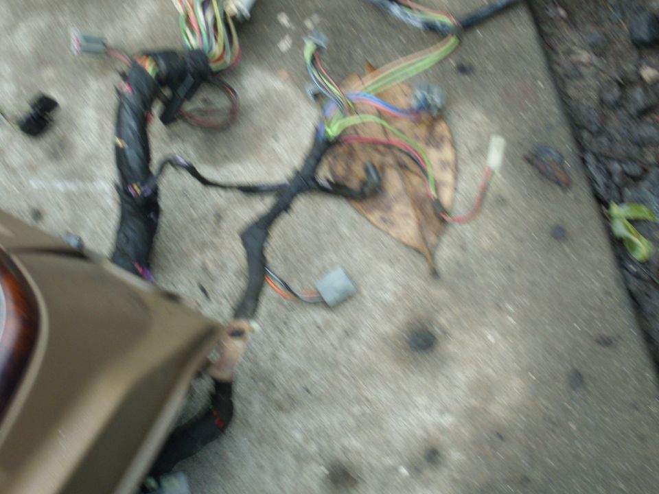 Vehicle wiring harness laid out on concrete, with a tan panel in the foreground