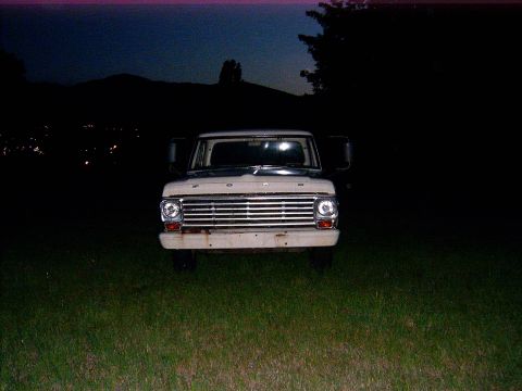 1967 Ford F-250 - A 1967 Ford F-250 truck is seen from the front, parked in a grassy field at twilight.