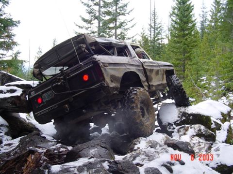 1989 Ford Bronco - Ford Bronco navigating a rocky, snow-covered trail in a wooded area.