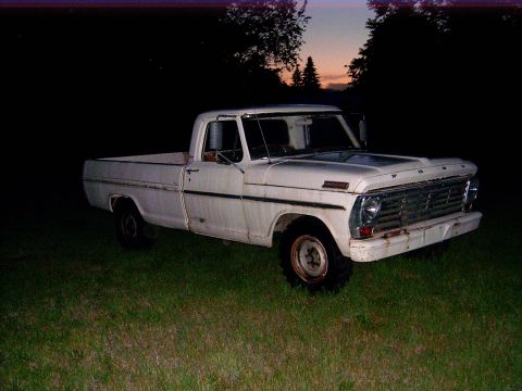 1967 Ford F-250 - White 1967 Ford F-250 pickup truck sits in a grassy field as the sun sets.