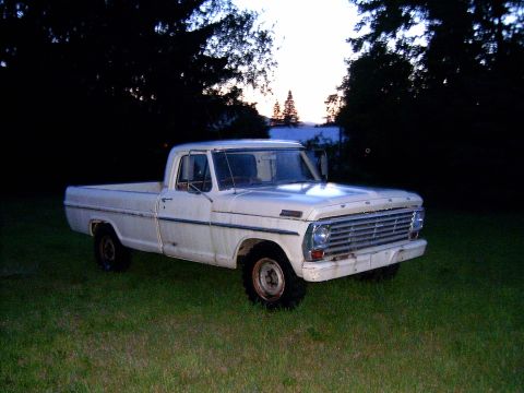 1967 Ford F-250 - A white 1967 Ford F-250 pickup truck is seen from a three-quarter front view, parked in a grassy area at dusk.