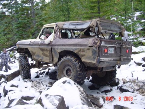 1989 Ford Bronco - A Ford Bronco navigates a rocky, snow-covered trail in a wooded area.