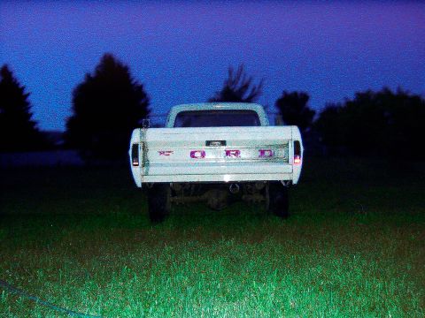 1967 Ford F-250 - A white Ford pickup truck is parked in a grassy field at twilight, showing its rear end.