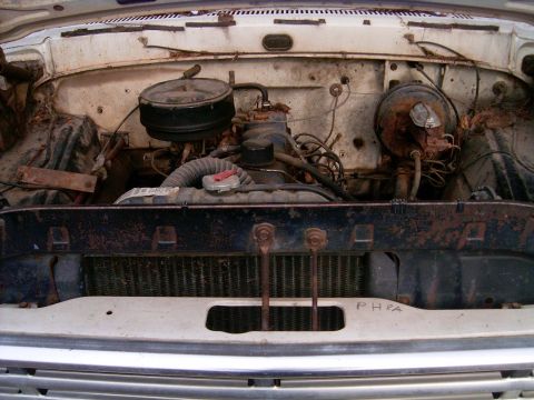 1967 Ford F-250 - The engine bay of a white 1967 Ford F-250 shows significant rust and wear, with the engine and radiator clearly visible.