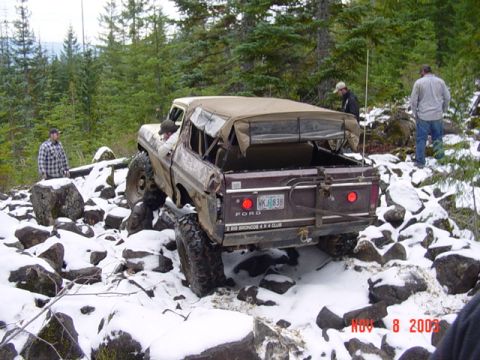 1989 Ford Bronco - A modified Ford Bronco navigates a challenging, snow-covered terrain with several onlookers present.