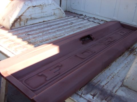 1967 Ford F-250 - Primed Ford tailgate with embossed lettering sits in the bed of a pickup truck.