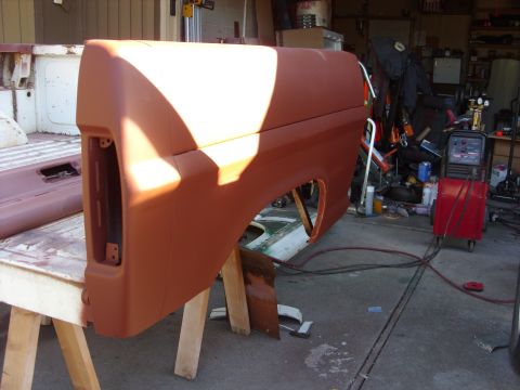 1967 Ford F-250 - A truck bed side panel, primed and resting on sawhorses, with a welding machine visible in the background.