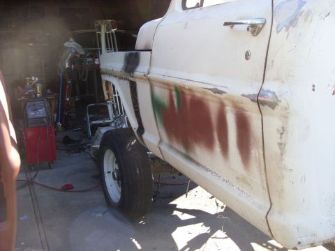 1967 Ford F-250 - A 1967 Ford F-250 truck is undergoing repairs in a garage, with visible primer and body damage.