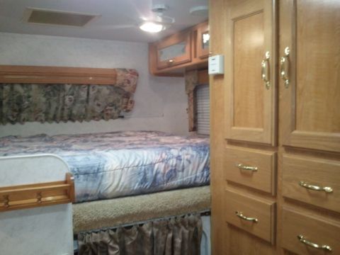 1967 Ford Mustang - Interior view of a camper showing a bed and wooden cabinets.