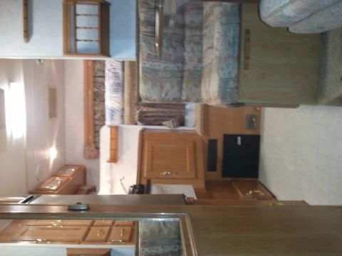 1967 Ford Mustang - The interior of a recreational vehicle shows wood cabinetry, a sink, and upholstered seating areas.