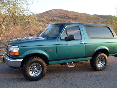 1996 Ford Bronco - This 1996 Ford Bronco is shown in a three-quarter front view against a backdrop of arid hills and sparse vegetation.