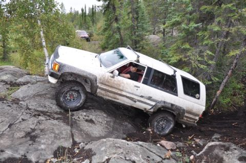 1986 Ford F-150 - A white SUV navigates a challenging off-road course with another vehicle visible in the background.