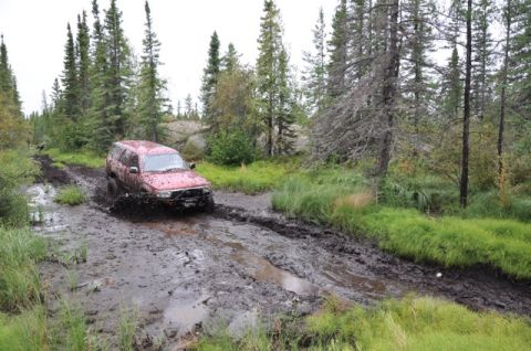 1986 Ford F-150 - Off-roading adventure goes wrong as a red SUV gets stuck in the mud.