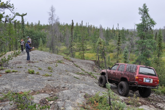 Red SUV with large tires navigating a rocky trail
