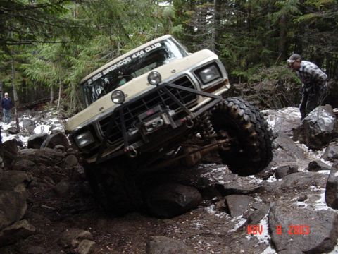 1989 Ford Bronco - A tan Ford Bronco navigates a rocky trail, with a "2 BIG BRONCOS 4X4 CLUB" sticker visible on the windshield.