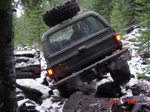 1989 Ford Bronco - Chevrolet K5 Blazer tackling a difficult off-road obstacle with snow and rocks.