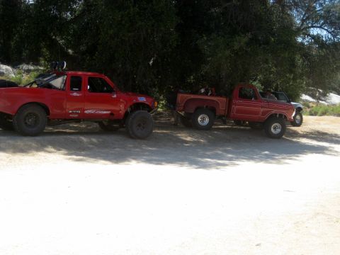 1996 Ford Bronco - Two modified trucks, one a 1970s Ford pickup, are parked side-by-side in a shaded area.