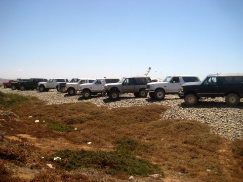 1996 Ford Bronco - Several Ford Broncos are parked in a row on a rocky terrain with sparse vegetation.