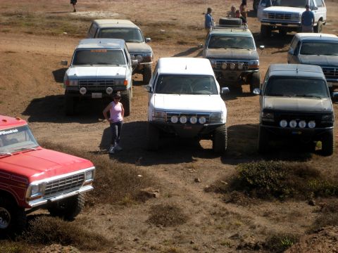 1996 Ford Bronco - A group of off-road vehicles are gathered in a dusty, outdoor area.