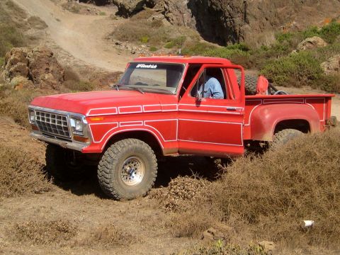1996 Ford Bronco - This red 1979 Ford F-150 pickup truck, modified for off-road use, is seen in a , dry landscape.