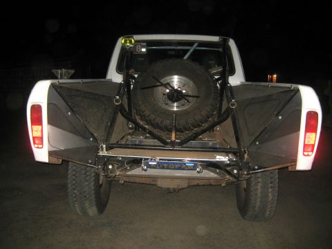 1996 Ford Bronco - This off-road truck features a spare tire and custom bed modifications, seen at night.