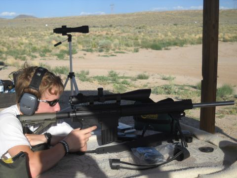 2012 Ford Mustang - A shooter takes aim with a sniper rifle equipped with a scope and bipod at an outdoor range.