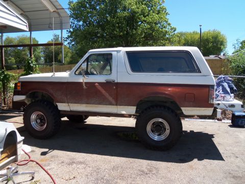 1989 Ford Bronco - Side view of a lifted 1987 Ford Bronco with brown and white paint, parked on a paved surface.