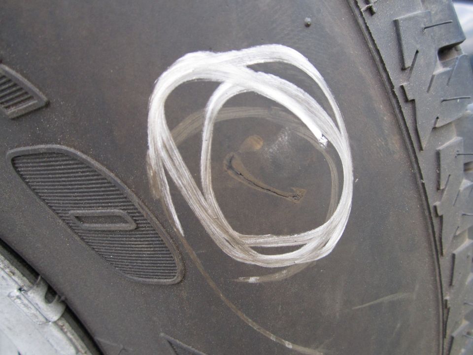 Tire sidewall with white chalk scribbles and a small crack