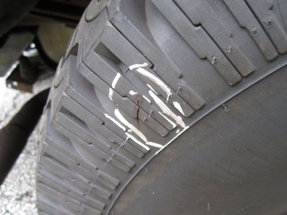 Close-up of a tire tread with white paint marks and a visible crack in the rubber