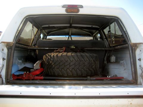 1996 Ford Bronco - The rear cargo area of an SUV is shown, equipped with a roll cage and a large spare tire.