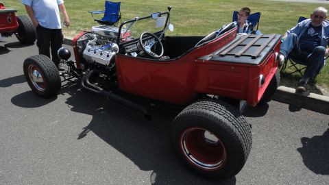 1964 Ford Fairlane - A custom red hot rod with a powerful V8 engine is parked outdoors with spectators nearby.
