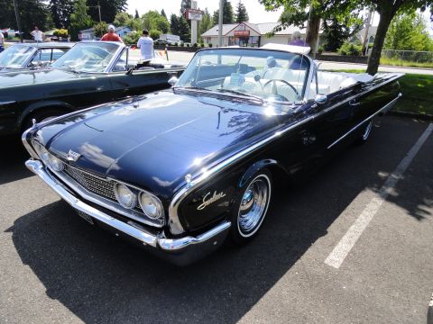 1964 Ford Fairlane - A classic convertible with prominent tail fins is parked in a lot on a sunny day.