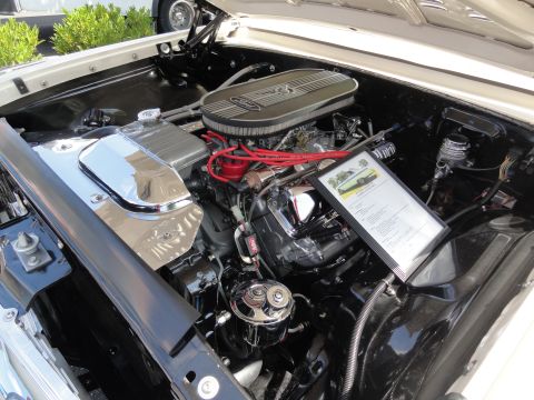 1964 Ford Fairlane - The engine bay of a 1964 Ford Fairlane features a V8 engine and a display document detailing the vehicle's specifications.