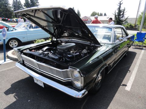 1964 Ford Fairlane - A dark green coupe with its hood open is parked next to a light blue convertible at an outdoor event.