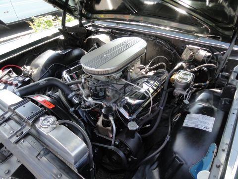 1964 Ford Fairlane - The engine bay of a black 1964 Ford Fairlane, a V8 engine with chrome accents and an aftermarket air cleaner.