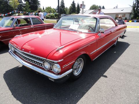 1964 Ford Fairlane - A red 1960 Ford Fairlane 500 coupe with chrome trim and a white interior is parked outdoors.