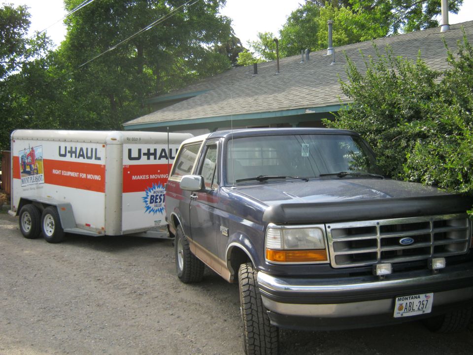 1994 Ford Bronco towing U-Haul trailer, front 3/4 view, blue