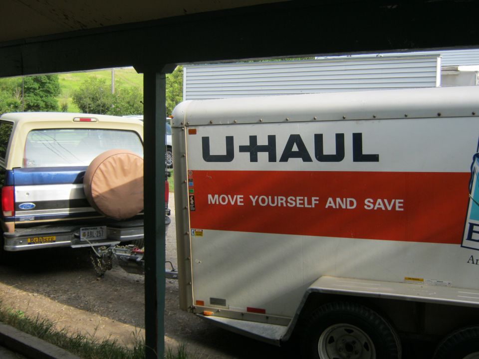 1994 Ford Bronco parked next to a U-Haul trailer. Bronco has a spare tire cover on the rear