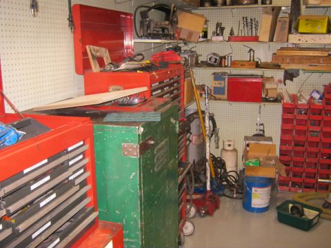 1994 Ford Bronco - A cluttered workshop scene features multiple toolboxes, shelves filled with tools, and various storage containers.