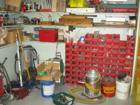 1994 Ford Bronco - A cluttered workshop scene displays shelves filled with tools and parts, organized in red bins, alongside various shop equipment.