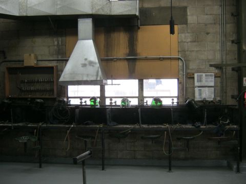 1994 Ford Bronco - A row of welding stations is set up in a workshop with a large ventilation hood overhead.