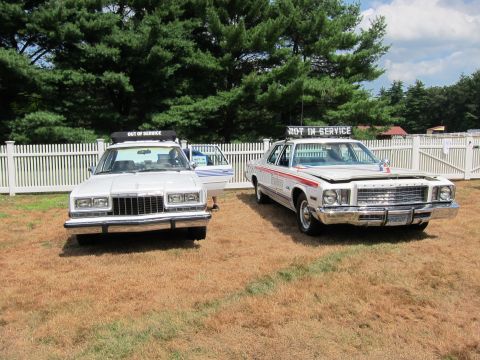 1991 Ford LTD Crown Victoria - Two white 1970s full-size police sedans displaying 'Out of Service' and 'Not In Service' signs parked on a grassy field.