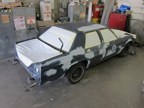1991 Ford LTD Crown Victoria - A 1991 Ford Crown Victoria is prepped for painting in a workshop, with windows taped and bodywork underway.