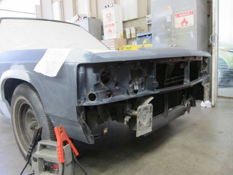 1991 Ford LTD Crown Victoria - A car's front end is being prepped for repair, with a battery charger connected.