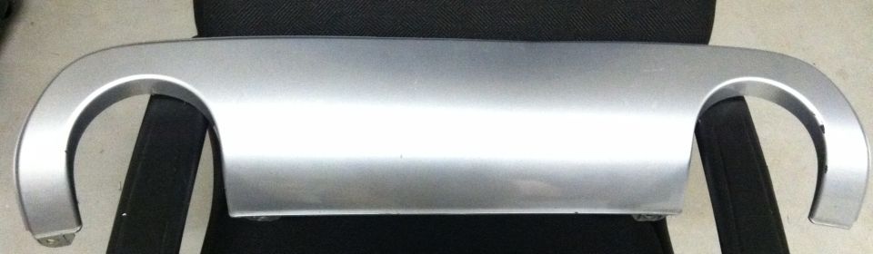 Silver rear bumper trim piece with two curved cutouts